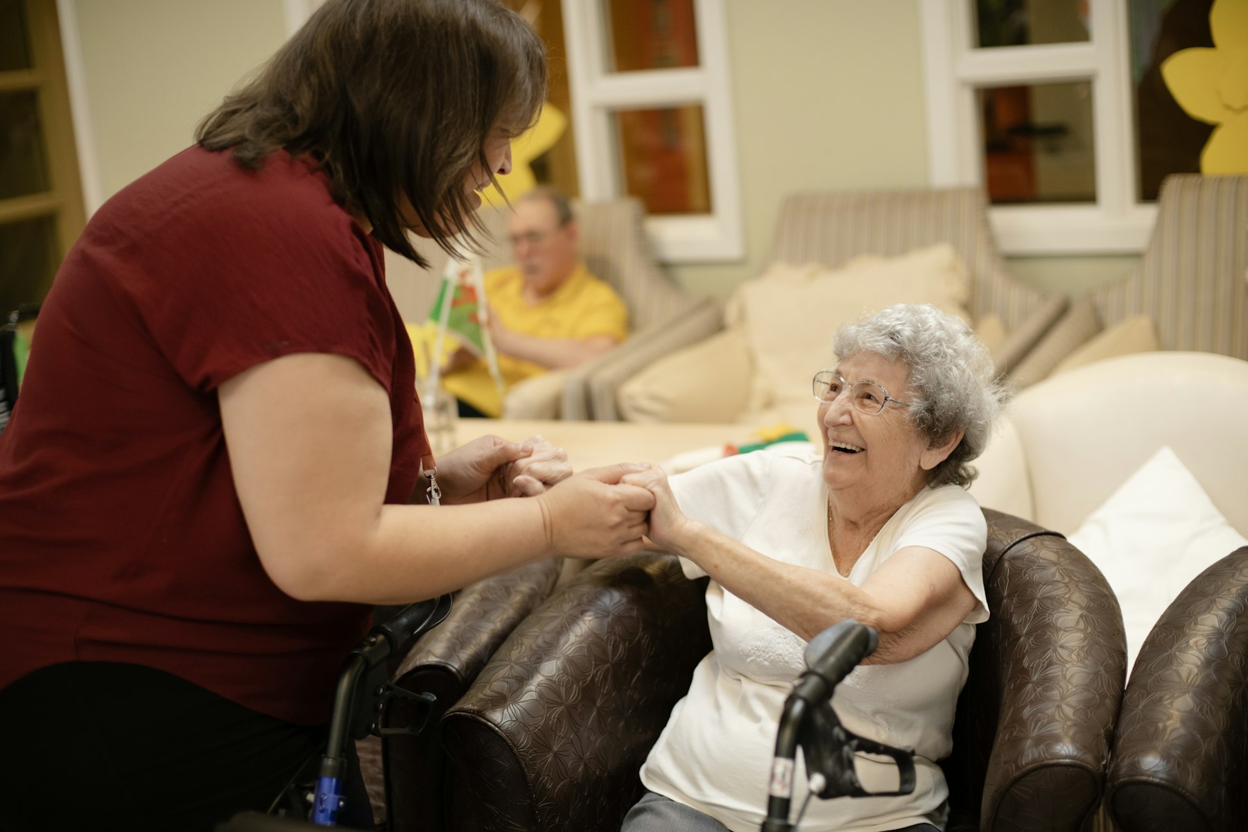 Care worker supporting an elderly resident in a care home lounge